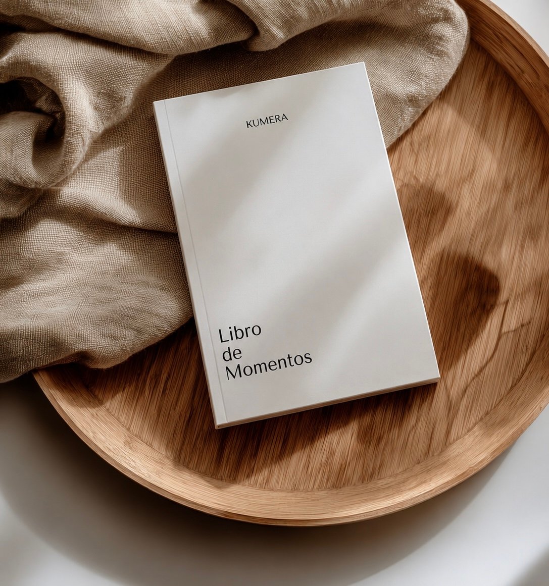 Libro de Momentos, el diario de KUMERA, sobre una bandeja de madera con un paño de lino.