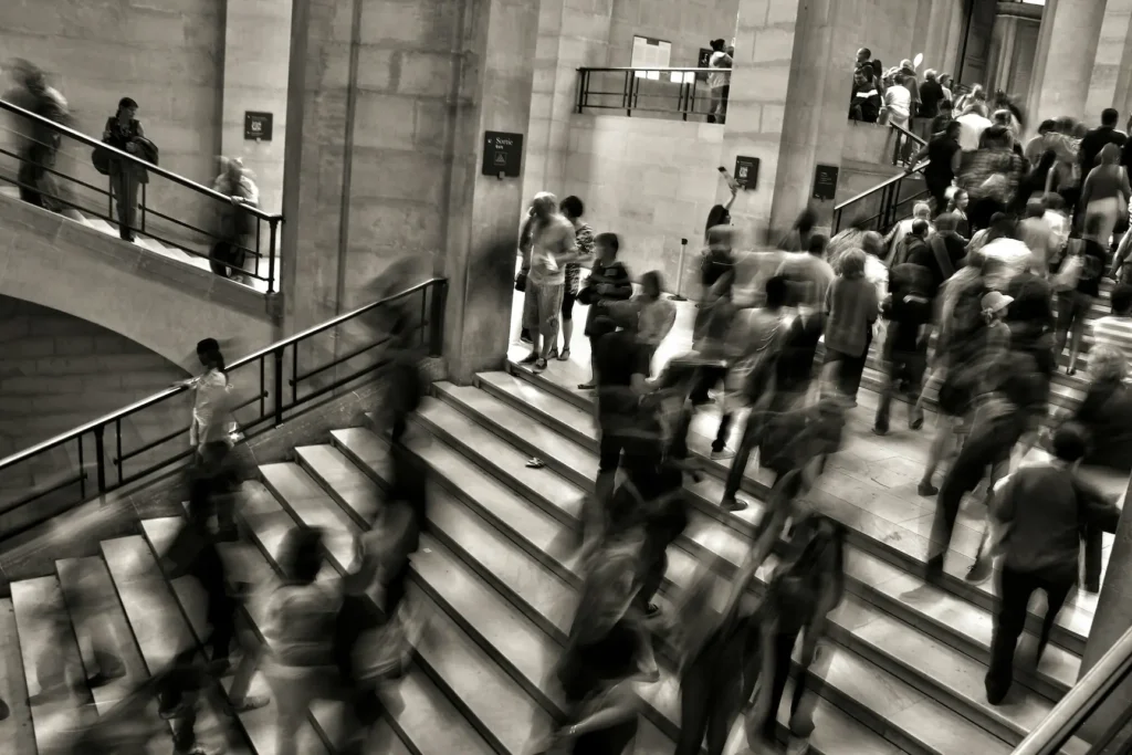 Multitud borrosa subiendo y bajando unas escaleras de piedra, en blanco y negro