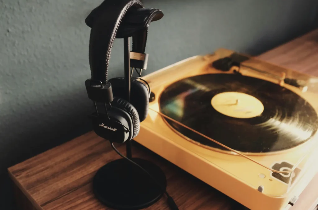 Unos auriculares colgados de un soporte junto a un tocadiscos con un vinilo
